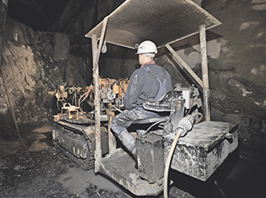 een arbeider zit op een graafmachine in een mijnschacht