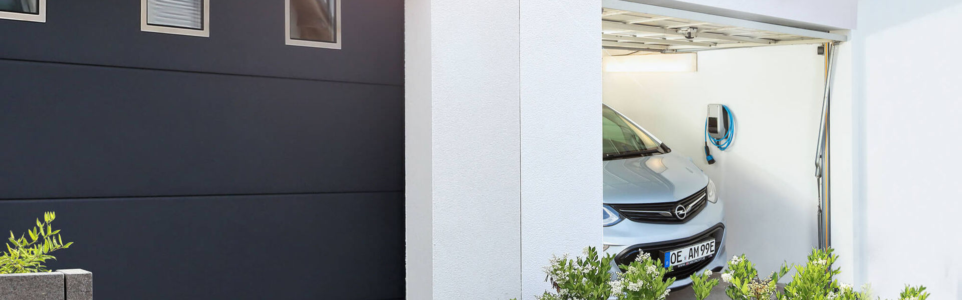 In einer schmalen Garage hängt die MENNEKES Wallbox AMTRON® Compact 2.0 an der Wand.