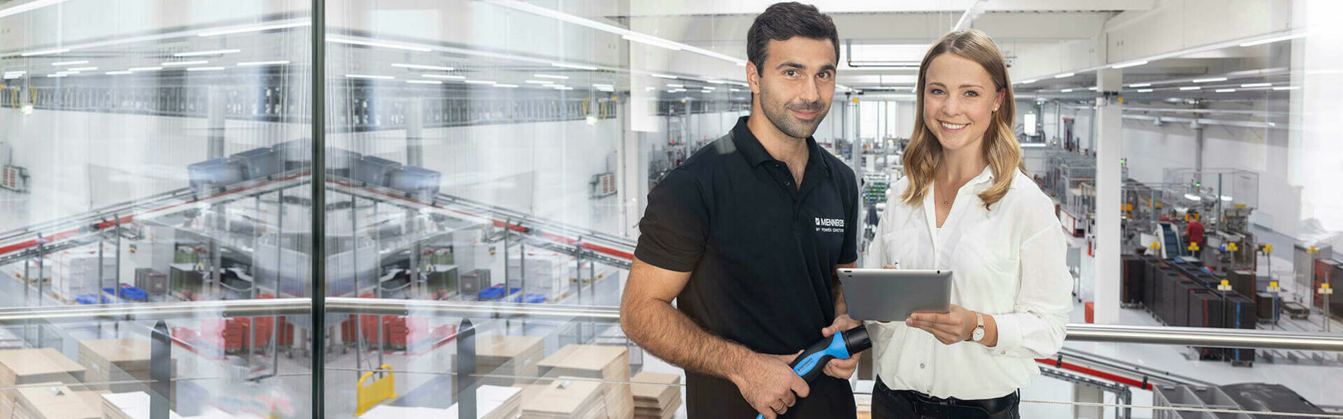 Zwei Frauen und zwei Männer stehen an einer langen, weißen Tafel und schauen auf ein Tablet